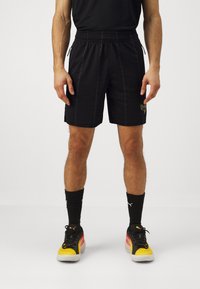 Pantaloni sportivi neri in rete con vita elasticizzata, dotati di tasche laterali e discreto marchio sulla gamba sinistra.