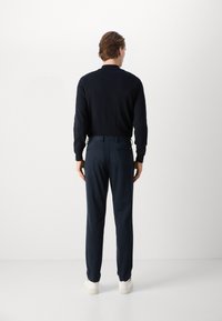 Navy long-sleeve pullover and matching trousers, both made of smooth fabric. Casual fit with a simple design and white sneakers.