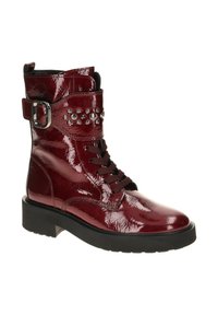 Red patent leather ankle boot with a lace-up front, side buckle, and metallic studs on the strap. Features a chunky black heel.