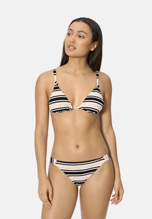 Mujer con cabello largo y oscuro, vestida con un top de bikini triangular a rayas en rosa pálido y negro, y braguitas de bikini a juego de tiro bajo, de pie frente a un fondo liso.