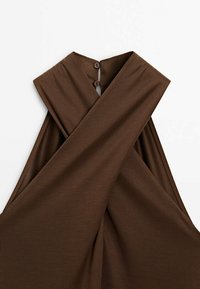 Haut marron sans manches avec encolure halter croisée et deux boutons au col arrière sur fond blanc.
