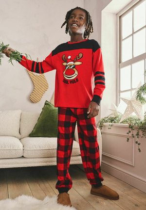 Roter Pyjama-Anzug mit einem Langarmshirt, das ein Rentier-Design und schwarze Akzente aufweist, kombiniert mit schwarz-roten karierten Hosen.