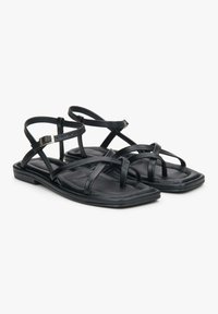 Zwarte leren sandalen met meerdere gekruiste banden, een platte zool en een rechthoekige vorm. Verstelbare gespaccenten op de enkelbanden.