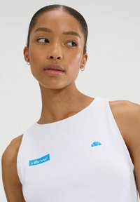 Biały bezrękawnik z niebieskimi akcentami logo. Posiada okrągły dekolt i gładką teksturę, podkreślając minimalistyczny design.