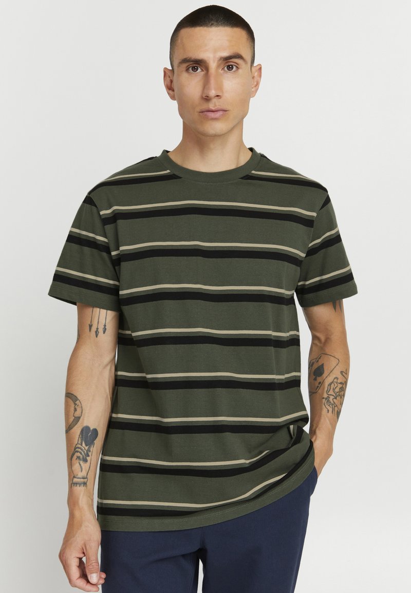 Camiseta de color verde oscuro con rayas horizontales en beige y negro. Mangas cortas, cuello redondo, fabricada en suave algodón, con un corte relajado.