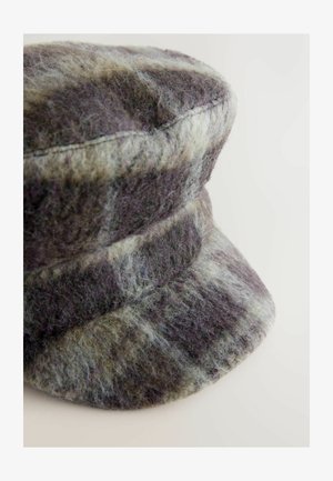 Pilkas vilnonis kepurė su tekstūrizuota, pūkuota paviršiumi. Turi siaurą kraštą ir apvalią, struktūrizuotą viršūnę su horizontaliomis siūlėmis.