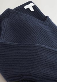 Granatowy sweter z ribbed knit z dekoltem w serek i widoczną białą metką na jasnym tle.