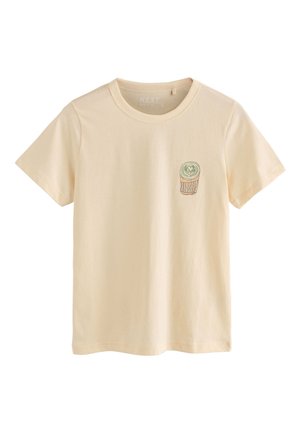 T-shirt beige à manches courtes avec col rond et petite illustration verte d'une tasse à café latte art sur la poitrine gauche.