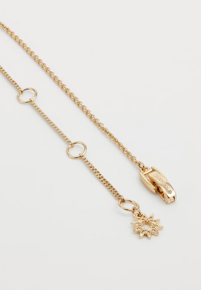 Gold chain featuring interlinked loops, a lobster clasp, and a sun-shaped charm with textured rays and a central opening.