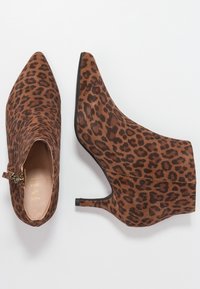 Stivaletti alla caviglia in stampa leopardata con punta affilata, realizzati in suede. Presentano una chiusura laterale con cerniera e un tacco sottile e alto. Colore: marrone e nero.