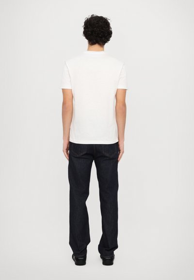 Hvid bomulds t-shirt med korte ærmer, parret med mørk denim jeans. T-shirten har et simpelt design, uden synlige logoer eller mønstre.