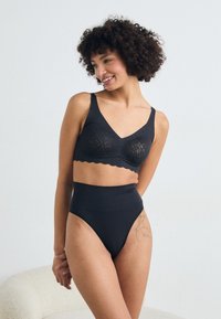 Zwarte kanten bralette met geëmboste randen en brede schouderbanden, gecombineerd met hoge zwarte slipjes, die een soepele textuur en een minimalistisch ontwerp hebben.