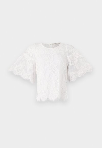 Blusa bianca in pizzo con maniche corte a campana, scollatura tonda e orlo ondulato. Sulla stoffa sono visibili delicati motivi floreali.