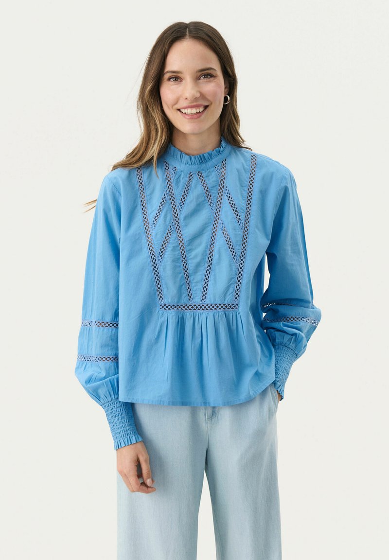 Blusa azzurro chiaro con scollo alto, caratterizzata da dettagli in pizzo elaborati e maniche a sbuffo, vita arricciata e vestibilità morbida.