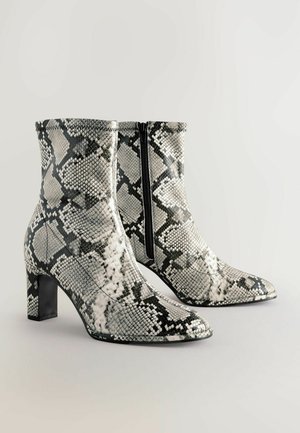 Spitz zulaufende Ankle Boots im Schwarz-Weiß-Schlangenprint, mit einem seitlichen Reißverschluss und einem stabilen Blockabsatz.