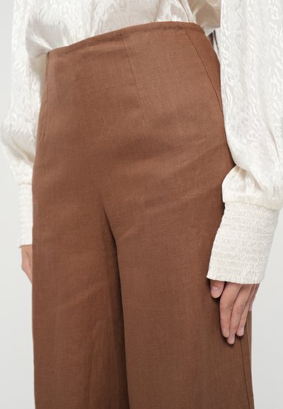 Pantaloni din in maro, cu talie înaltă, având un design cu picioare drepte, caracterizați printr-o textură netedă și detalii minime la cusături.