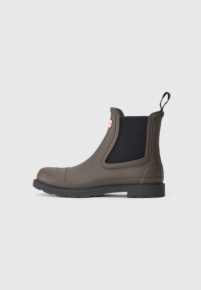 Bottines Chelsea en caoutchouc vert olive foncé avec des panneaux latéraux élastiques noirs, une languette et une semelle noire texturée pour une meilleure adhérence.