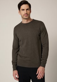 Ciemnozielony dziany sweter z okrągłym dekoltem, ściągaczami na rękawach i na dole. Miękka tekstura, dopasowany fason i długie rękawy.