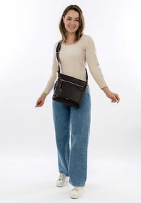 Brown leather crossbody bag with a textured surface, featuring a front zip pocket, adjustable strap, and silver accents. Size: medium.