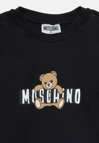 Μαύρο παιδικό πουκάμισο Moschino με γραφική απεικόνιση μιας αρκουδίτσας ενσωματωμένη σε λευκά γράμματα που σχηματίζουν τη λέξη "MOSCHINO".