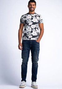 Herre t-shirt med korte ærmer i sort med hvide og lyserøde blomster, kombineret med mørkeblå jeans og hvide sneakers. Casual pasform og design.