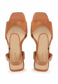 Sandales à talons en daim beige avec un nez carré et un dos ouvert. Dotées d'une large bande avant et d'une fine bride de cheville avec du matériel en ton doré.