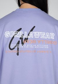 Purple cotton t-shirt featuring bold black and white text, with orange accents. Text reads "GORILLAWEAR" and "UNITED STATES OF AMERICA."