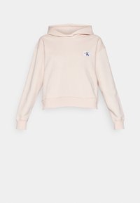 Sweat à capuche court beige clair avec manches longues, une poche sur le devant, une capuche et un petit patch logo "CK" sur la poitrine gauche.