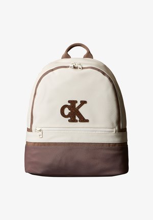 Zaino compatto beige e marrone con tasca frontale con cerniera e logo marrone "cK" centrato sul pannello frontale superiore.