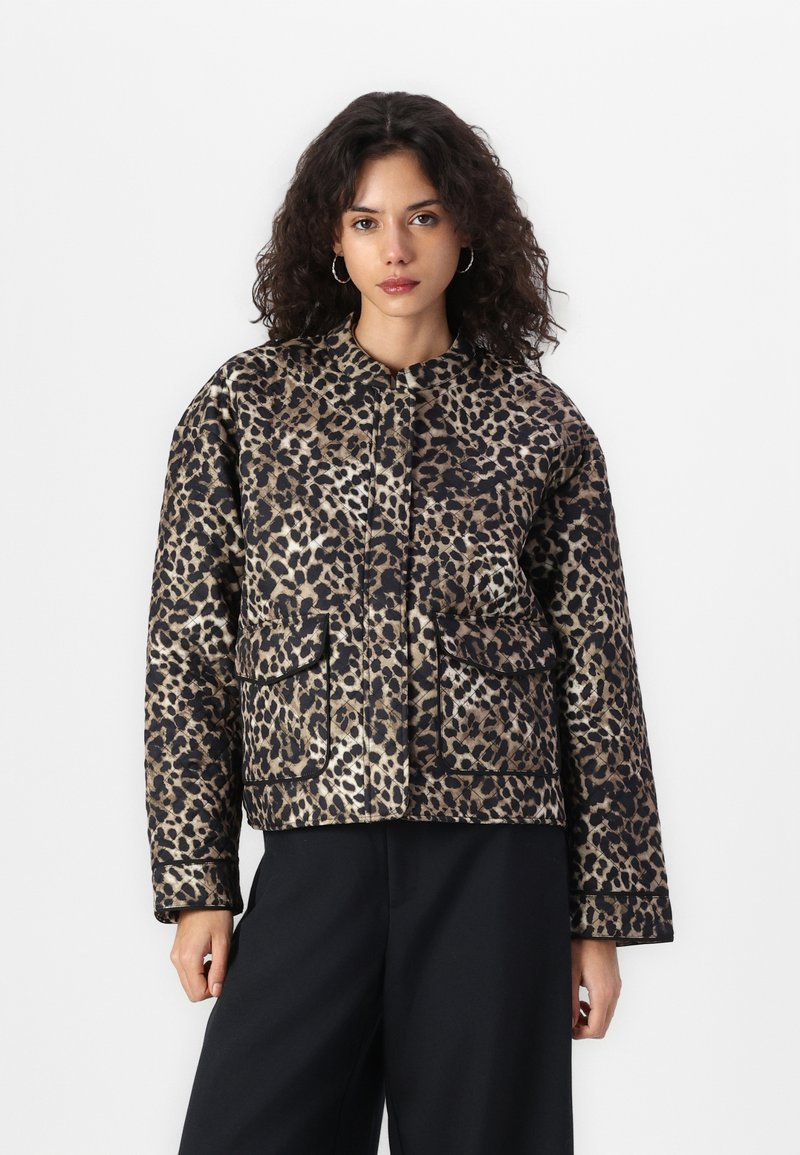 Veste à imprimé léopard avec un col rond, des poches avant et une texture matelassée. La palette de couleurs comprend des nuances de beige, noir et des accents de crème.
