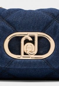 Geantă din denim cu o textură matlasată, având un element de închidere proeminent în ton de aur și o culoare albastru închis. Accentuata de detalii cu cusături.