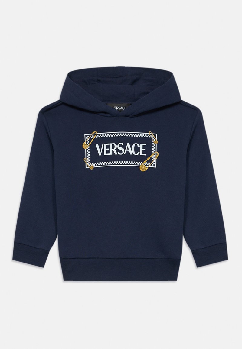 Temno modra majica s kapuco, z belim logotipom "VERSACE" v pravokotnem dizajnu in zlatimi varnostnimi iglami kot dodatki. Iz bombažnega materiala.