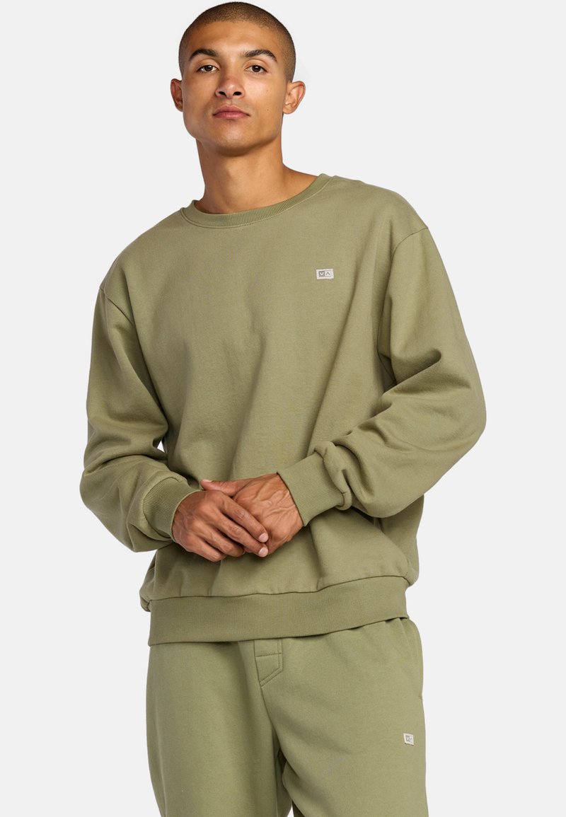 Olivengrüner Sweatshirt, Rundhalsausschnitt, gerippte Ärmelbündchen, lockere Passform, mit aufgesticktem Logo-Patch auf der Brust, aus weichem, strukturiertem Stoff.