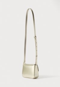 Majhna torbica �čez ramo iz kovinskega zlatega usnja z nastavljivim trakom in zlato kovinsko opremo na belem ozadju.