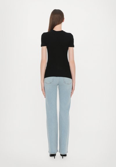 Black short-sleeve t-shirt paired with light blue straight-leg jeans, featuring a high waist and subtle back pockets. Black heels complete the look.