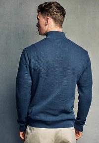 Pullover blu navy con texture, colletto alto, polsini e orlo a costine, caratterizzato da un motivo a nido d'ape e una vestibilità comoda.