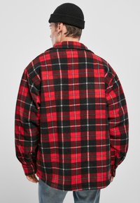 Piros és fekete kockás flaneling, laza szabással, hosszú ujjal és gombos mandzsettával. Puha textúra és klasszikus kockás minta.