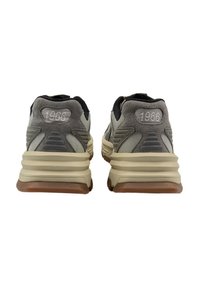 Graue und beige Sportschuhe mit einer gepolsterten Sohle, ausgestattet mit einem Netz-Obermaterial, Wildleder-Akzenten und der Nummer "1966" an der Ferse.