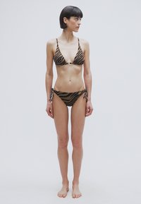 Σετ μπικίνι με animal print που περιλαμβάνει τοπ τρίγωνο με λεπτές τιράντες και κάτω μέρος με χαμηλή μέση και δεσίματα στα πλάγια. Τα χρώματα είναι καφέ και μαύρο.