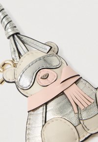 Breloc ursuleț din piele argintie și bej, cu eșarfă roz, având un finisaj metalic și detalii în urechi și ochi. Are o agățare cu ciucure.