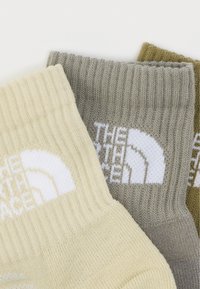 Τρία ριμπ πλεκτά κάλτσες σε μπεζ, γκρι και ελιά, κάθε μία με λευκό λογότυπο «The North Face» στη μανσέτα.