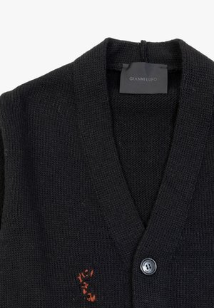 Czarny sweter robiony na drutach z dekoltem w serek, z przodu z zapięciem na guziki i haftowanym detalem w kolorze pomarańczowym po lewej stronie.