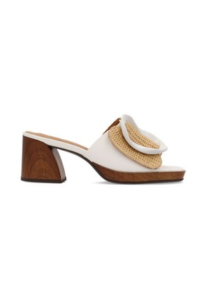 Mule bianco con punta aperta, tacco in legno a blocco e grande fibbia decorativa intrecciata sulla fascetta superiore su sfondo bianco.