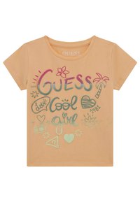 Peachfarvet bomulds t-shirt med korte ærmer, der har multikolorede grafik, herunder "Guess," hjerter, en blomst og et palmetræ.