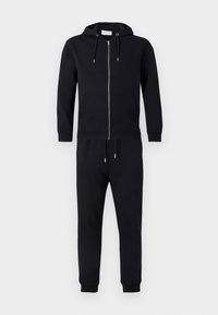 Μαύρη φούτερ ζακέτα με φερμουάρ, κορδόνια, μπροστινές τσέπες και παντελόνι jogger που ταιριάζει. Κατασκευασμένη από απαλό ύφασμα με ριμπ τελειώματα στα μανίκια και στη μέση.