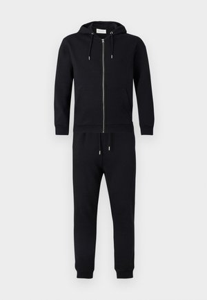 Černá mikina na zip s kapucí a šňůrkami, předními kapsami a odpovídajícími tepláky. Vyrobeno z měkké látky s žebrovanými manžetami a pasem.