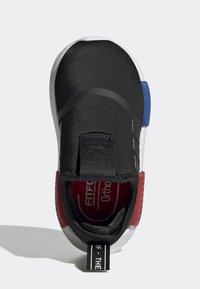 Svart slip-on sneakers med en strukturerad ovandel, vit sula, röda och blå detaljer, ett svart rem och en framträdande dragtag vid hälen.