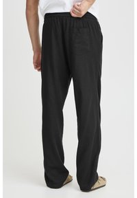 Black linen pants with a relaxed fit, elastic waistband, and a single back pocket. The fabric has a smooth texture and minimal wrinkles.
