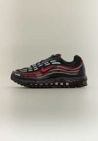 Chaussure de sport noire et rouge avec tige en mesh, accents réfléchissants, et semelle coussinée. Présente un design ondulé distinctif et un amorti pneumatique prononcé.
