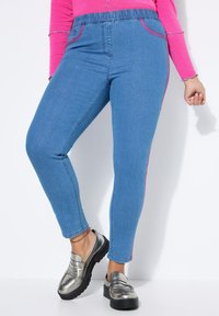 Lichte blauwe denim joggers met een gladde textuur, voorzien van roze zijstrepen en een elastische tailleband. Gecombineerd met metallic instapschoenen.